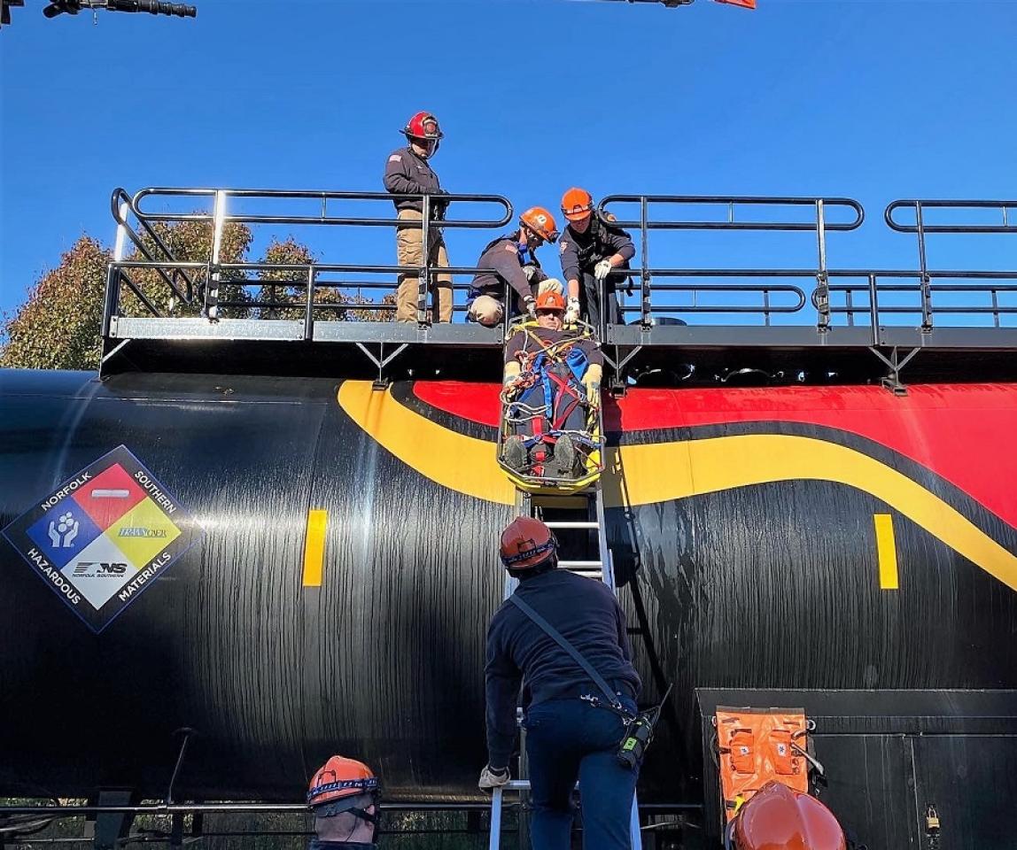 Men participating in fireman rope training exercise near a train.