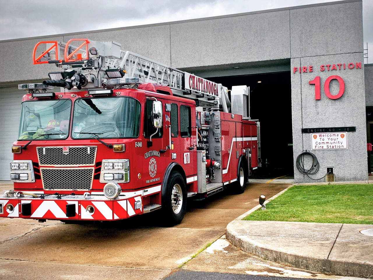  Exterior of Fire Station 10 with red brick walls, white garage doors, and a flag flying on a pole.