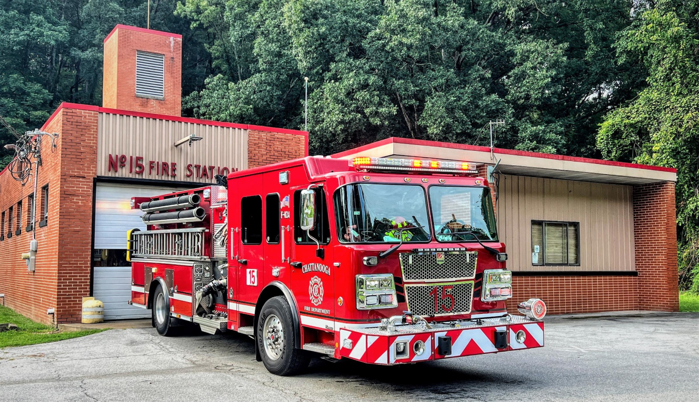 Front view of Fire Station 15 with firefighter emblem on the facade and a fire truck parked outside.