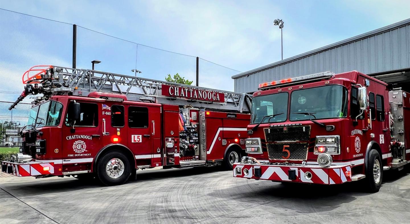 Two red fire trucks parked in front of a building at fire station 5.