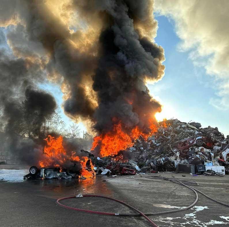 Burning scrap metal pile visible across the area