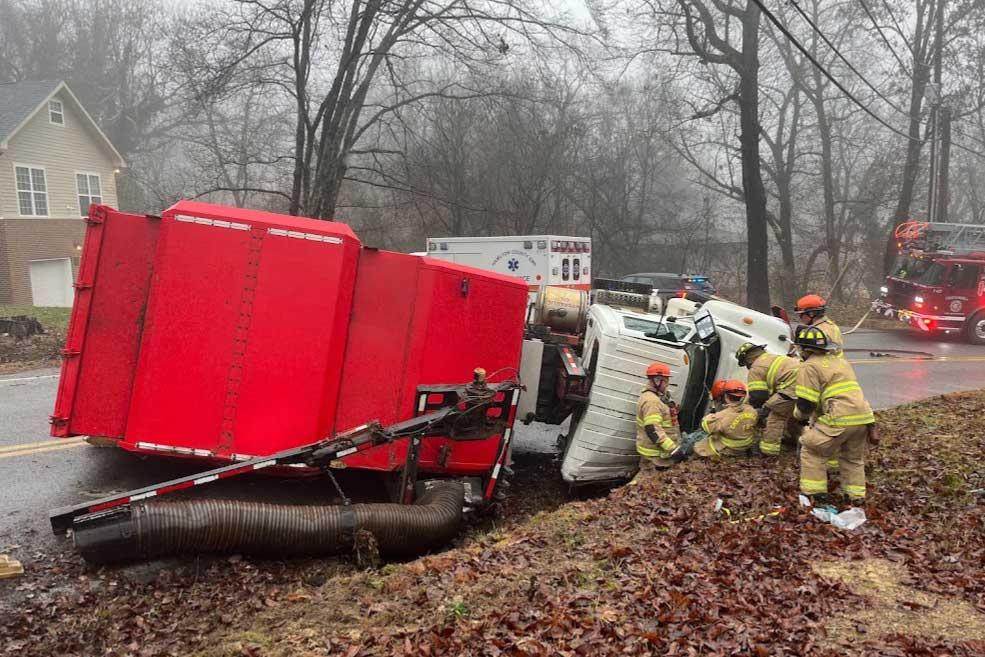 Firefighters extricate driver trapped in overturned debris truck